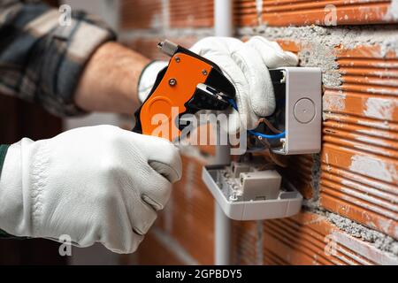 Elektriker Arbeiter bei der Arbeit mit Abisolierer bereitet die elektrischen Kabel der häuslichen elektrischen Anlage. Bauindustrie. Stockfoto