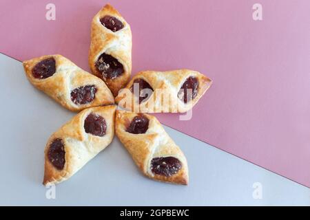 Auf einem zweifarbigen Hintergrund, köstliche Blätterteig Plätzchen gefüllt mit Himbeermarmelade. Draufsicht mit Kopierbereich. Flach liegend Stockfoto