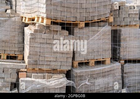 Graue Steine auf dem hölzernen Paletten auf dem Boden im Freien Stockfoto