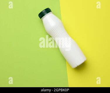 Weiße Plastikflasche für Milch auf grünem Hintergrund, Behälter für flüssige Produkte, flaches Lay Stockfoto