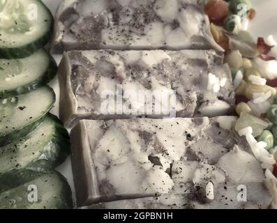 Auf dem Tisch auf einem Teller mit köstlichen Fleisch Vorspeise: Gefüllt mit Fleisch und Speck Schweinefleisch Magen, in Scheiben geschnitten, neben Gemüse und frischen Gurken. Top Vie Stockfoto