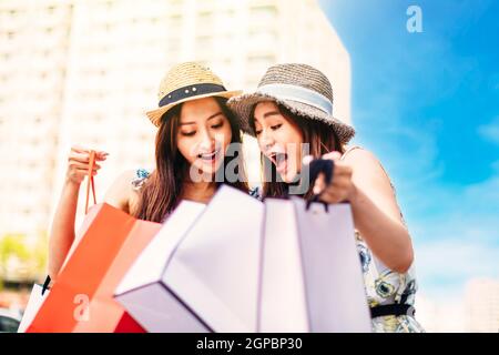 Überrascht junge Frauen suchen die Einkaufstaschen Stockfoto