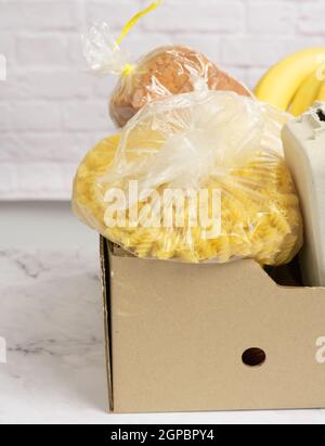 Karton mit verschiedenen Produkten, Obst, Nudeln. Spendenkonzept Stockfoto