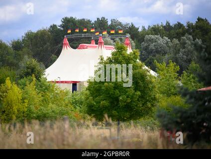 Templin, Deutschland. September 2021. Zwischen Bäumen im South Industrial Park steht ein Zirkuszelt mit acht wehenden deutschen Fahnen auf dem Dach. (To dpa: 'Die Hamptons von Berlin? Ein Blick auf Merkels Heimat, die Uckermark') Quelle: Soeren Sache/dpa-Zentralbild/dpa/Alamy Live News Stockfoto