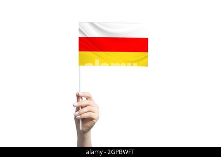 Schöne weibliche Hand hält Südossetien Flagge, isoliert auf weißem Hintergrund. Stockfoto