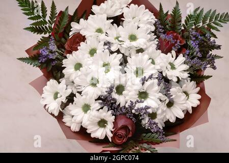 Ein wunderschön gestalteter Strauß aus weißen Chrysanthemen und roten Rosen auf hellem Hintergrund. Draufsicht, Nahaufnahme. Stockfoto