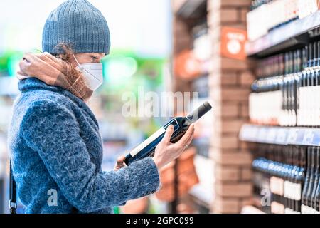 Junge Frau wählt Wein in einem Weinladen. Stockfoto