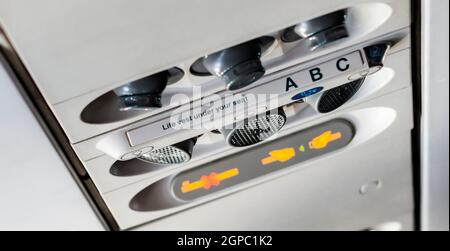 Bedienfeld für individuelle Klimaanlagen und Leuchten in einem kommerziellen Verkehrsflugzeug. Kunststoffknöpfe und Sicherheitsanzeige. Flugreise Stockfoto