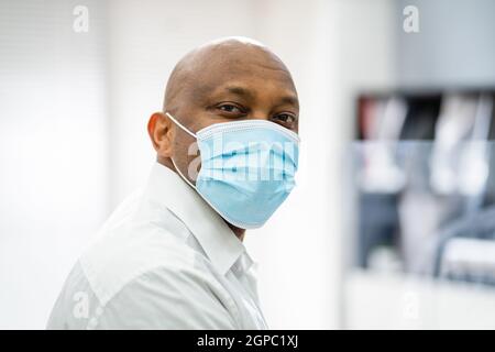 Mann An Der Rezeption Mit Medizinischer Maske An Der Rezeption Des Büros Stockfoto