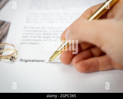 Heiratsvertrag mit zwei goldenen Eheringen und Goldstift, prenuptial Vereinbarung, Makro Nahaufnahme, unterzeichnen mit signanture, Dokument, Vereinbarung Konzept ro Stockfoto