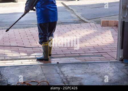 Terrassendruckreinigung. Kaukasische Frau, Die Seine Terrasse Auf Dem Betonboden Mit Einem Wasserreiniger Mit Hohem Druck Wäscht. Stockfoto