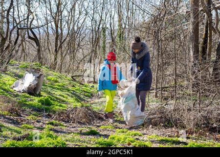 Familie sammelt Müll im Wald in einer großen Tasche Zum Recycling Stockfoto