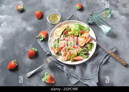 Hühnersalat mit Avocado, Erdbeeren, Blauschimmelkäse, Rucola, Rübenblättern. Gesundes Mittagessen Avocado Schüssel, Teller mit Huhn und Erdbeeren auf der da Stockfoto