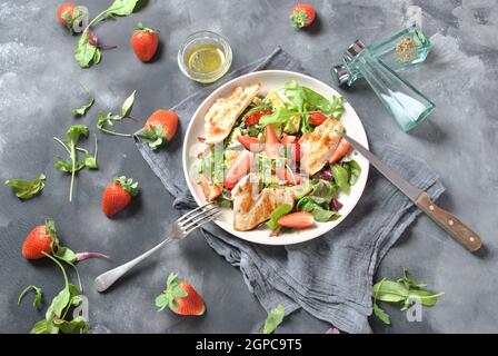 Hühnersalat mit Avocado, Erdbeeren, Blauschimmelkäse, Rucola, Rübenblättern. Gesundes Mittagessen Avocado Schüssel, Teller mit Huhn und Erdbeeren auf der da Stockfoto