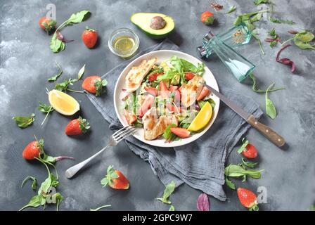 Hühnersalat mit Avocado, Erdbeeren, Blauschimmelkäse, Rucola, Rübenblättern. Gesundes Mittagessen Avocado Schüssel, Teller mit Huhn und Erdbeeren auf der da Stockfoto