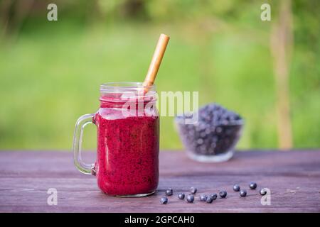 Köstlicher Heidelbeer-Smoothie in einem Glas-Becher auf dem Tisch, aus nächster Nähe Stockfoto