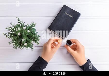 Junge Frau beten und Kommunion nehmen - der Wein und das Brot Symbole von Jesus Christus Blut und Körper mit der Heiligen Bibel. Ostern Passah und Lord Su Stockfoto