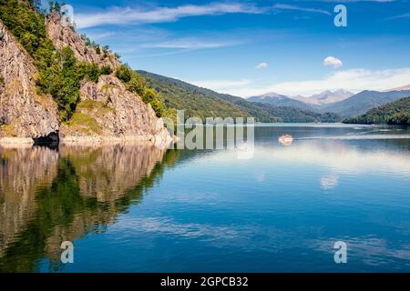 Blick auf den Vidraru See in den Karpaten. Strahlend blauer Himmel und grüne Bäume. Bootstour auf dem Wasser. Negativer Kopierbereich, für Text platzieren. T Stockfoto