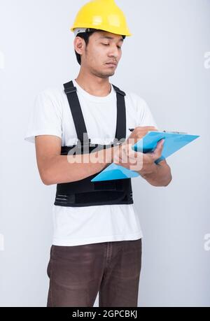 Arbeiter Mann Stand schreiben Buch schreiben Notiz trägt zurück Stützgurt Körperhaltung schützen Stockfoto