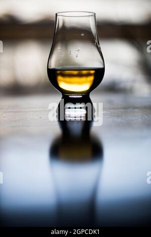 Farbe Nahaufnahme eine Hand hält ein Glencairn Whisky Glas auf einem Holztisch, mit geringer Schärfentiefe. Stockfoto