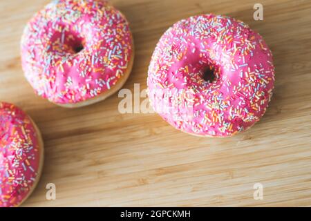 Zucker bestreut rosa Donut auf Holzplatte Stockfoto