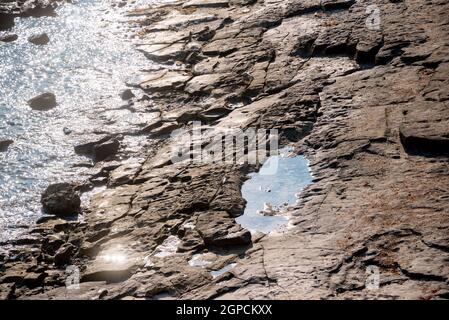 Natürlicher Hintergrund. Nahaufnahme mit schäbigen Felsspalten. Grau-braune Steinstruktur von Bergen. Farbe im Vintage- und verblassten matten Stil in getöntem Foto Stockfoto