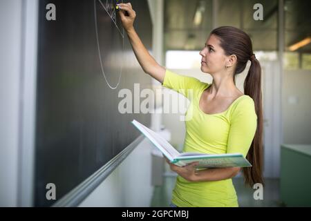 Junger Lehrer im Klassenzimmer Zeichnung ein Planimetrie-Problem auf der Tafel Stockfoto