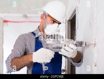 Porträt eines reifen Reparaturers, der mit einem Bohrer in Innenräumen steht Stockfoto