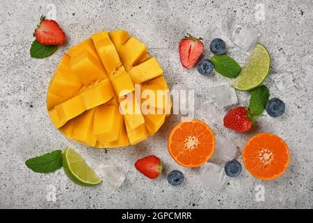 Nahaufnahme Zubereiten von frischen reifen geschnittenen Mango- und Mischobst-Dessert auf grauem Stein Schneidebrett, erhöhte Draufsicht, direkt darüber Stockfoto
