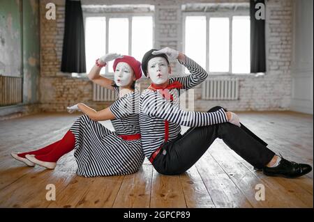 Männliche und weibliche Pantomime Künstler sitzen auf dem Boden, Liebespaar Parodie Szene, Comedy. Pantomime Theater, Komiker, positive Emotion, Humor Leistung Stockfoto