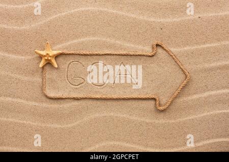 Pfeil aus Seil und Meer Muscheln mit dem Wort Goa auf dem Sand, als Hintergrund Stockfoto