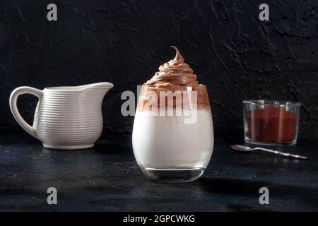 Dalgona kalter Kaffee mit Zutaten und Platz für Kopien auf schwarzem Schiefergrund Stockfoto