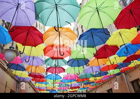 Farbige Regenschirme hängen oben. Set von verschiedenen Regenschirmen. Lokales Wahrzeichen. Mehrfarbige Regenschirme. Straßendekoration. Farbiger Entwurf des Exterio Stockfoto