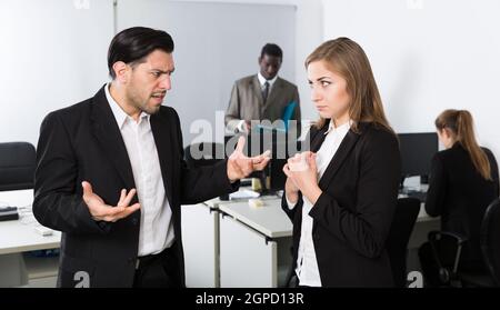 Verärgerter Mann Chef pointing zu vermissen in der Arbeit zu weiblich Stockfoto