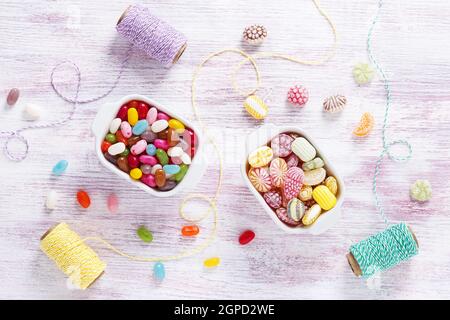 Bunte Bonbons und Jelly Beans in zwei weißen Keramikschalen. Draufsicht. Sweet Food und Feier Konzept. Stockfoto