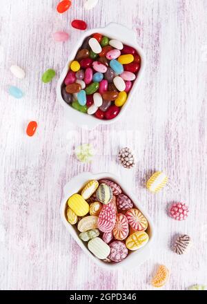 Zwei weiße Keramikschüsseln mit farbenfrohen Bonbons und Jelly Beans. Draufsicht. Stockfoto