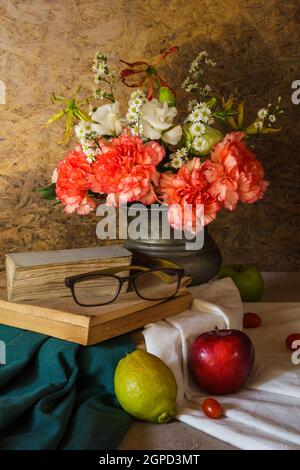 Stillleben mit Gläsern, die auf dem Buch ruhen, mit Früchten und Blumen in einer Vase. Stockfoto