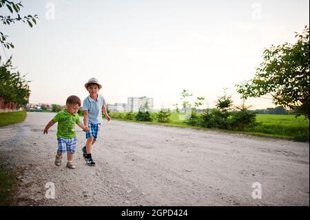 Zwei Brüder gehen und halten sich die Hände, Bruder liebt. Stockfoto