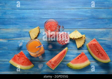 Frische Wassermelonen- und Ananascocktails in Gläsern auf blauem rustikalem Holzhintergrund. Kalter Sommer Wassermelone und Ananas Smoothie Stockfoto