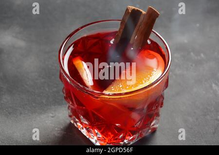 Negroni-Cocktail. Rauchiger italienischer Aperitivo mit Gin, Campari, martini rosso, Orange und Eiswürfeln, serviert im Glas auf dunklem Steingrund Stockfoto