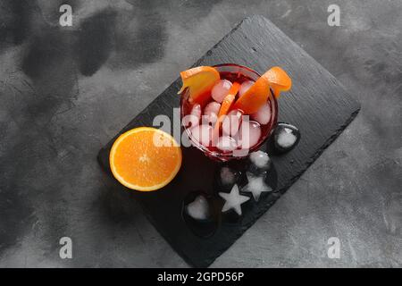 Negroni-Cocktail. Rauchiger italienischer Aperitivo mit Gin, Campari, martini rosso, Orange und Eiswürfeln, serviert im Glas auf dunklem Steingrund Stockfoto