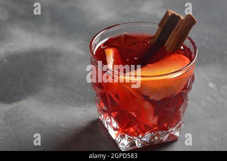 Negroni-Cocktail. Rauchiger italienischer Aperitivo mit Gin, Campari, martini rosso, Orange und Eiswürfeln, serviert im Glas auf dunklem Steingrund Stockfoto