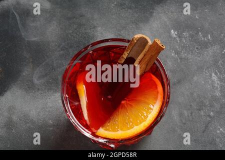 Negroni-Cocktail. Rauchiger italienischer Aperitivo mit Gin, Campari, martini rosso, Orange und Eiswürfeln, serviert im Glas auf dunklem Steingrund Stockfoto