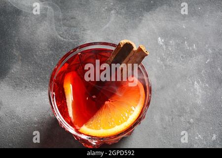 Negroni-Cocktail. Rauchiger italienischer Aperitivo mit Gin, Campari, martini rosso, Orange und Eiswürfeln, serviert im Glas auf dunklem Steingrund Stockfoto