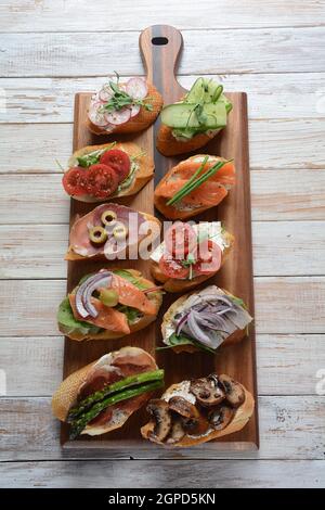 Brushetta oder traditionelle spanische Tapas. Vorspeisen mit italienischen Antipasti, Snacks. Vielzahl von kleinen Sandwiches mit Schinken, Tomaten, Lachs Stockfoto