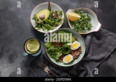 Vegan Buddha Schüssel mit Buchweizen, Avocado, gekochte Eier, Tomaten, Rucola Zuckerrüben Blätter, Zitrone. Gesunde, Detox, Diät Lebensmittel Konzept Stockfoto