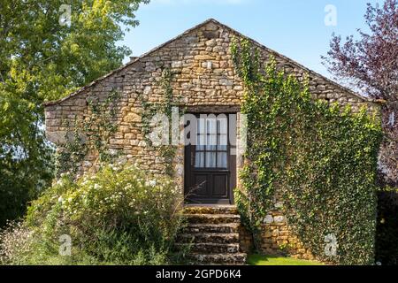 Mauer eines alten Steinhauses mit Efeue überwachsen Stockfoto