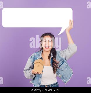 Happy Asian Portrait schöne nette junge Frau tragen Denim aufgeregt lächelnd halten Haus Modell und leere Rede Blase Zeichen, Studio erschossen auf schnurrem isoliert Stockfoto