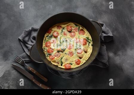 Frittata aus Eiern, Pilzen, Kirschtomaten und Spinat in einer Pfanne serviert. Italienische Küche. Stockfoto