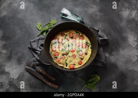 Frittata aus Eiern, Pilzen, Kirschtomaten und Spinat in einer Pfanne serviert. Italienische Küche. Stockfoto